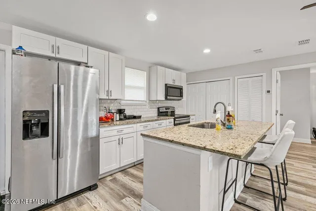 a kitchen with stainless steel appliances granite countertop a refrigerator and a stove top oven