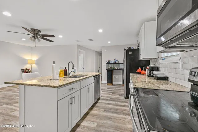 a kitchen with stainless steel appliances granite countertop a sink a stove and a refrigerator