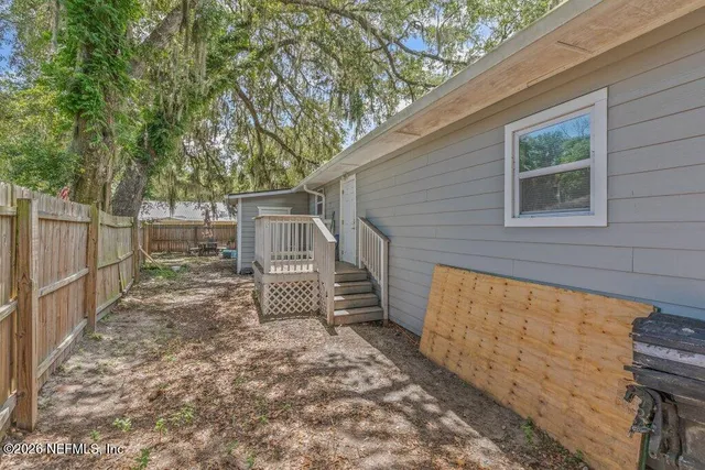 a view of a house with backyard and wooden fence