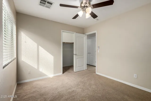 an empty room with windows and fan