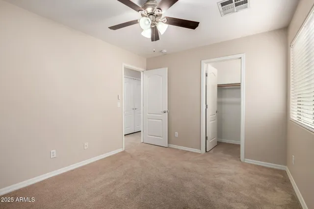 a view of an empty room and chandelier fan