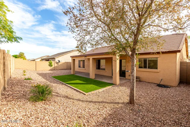 a view of a white house next to a yard with a large tree