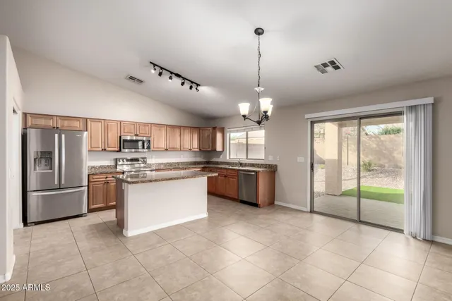 a kitchen with stainless steel appliances granite countertop a refrigerator a sink dishwasher a stove and white cabinets with wooden floor