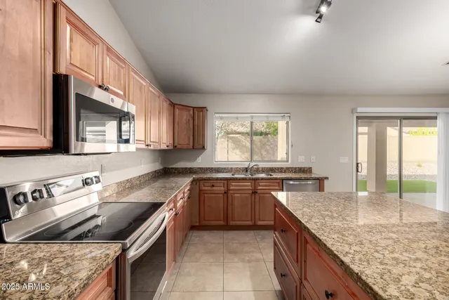 a kitchen with kitchen island granite countertop a stove sink and cabinets