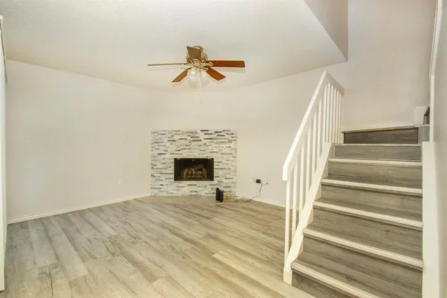 a view of an empty room with wooden floor fireplace and a window