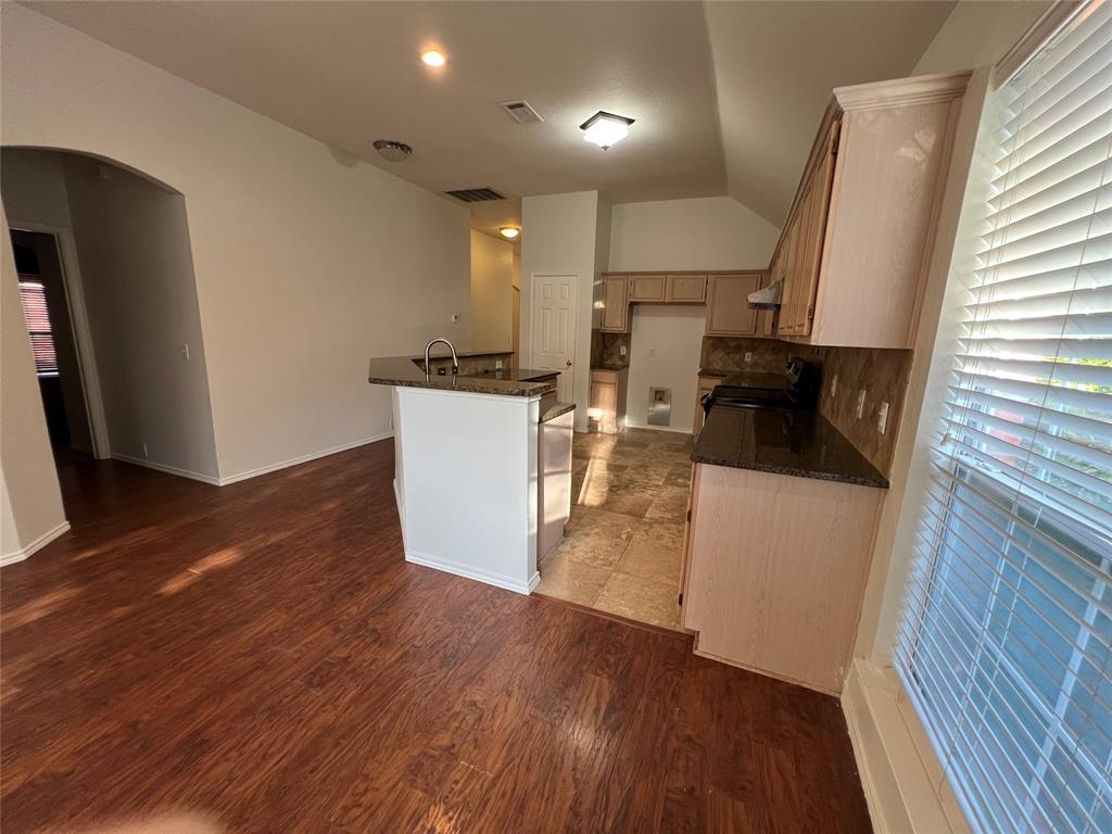 334 Touchdown Drive Irving, TX 75063 - Photo 11 of 32 Open-concept kitchen featuring dark granite countertops, light wood-finish cabinetry, a tile backsplash, and a built-in oven range