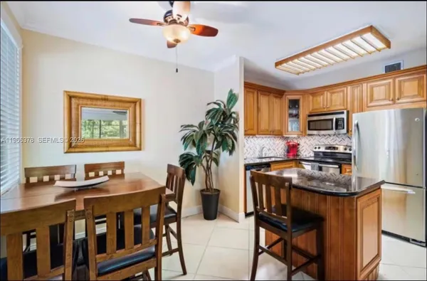 a kitchen with stainless steel appliances granite countertop a stove a refrigerator a sink a dining table and chairs with wooden floor