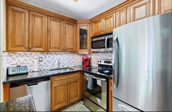 a kitchen with stainless steel appliances granite countertop a refrigerator and a stove top oven