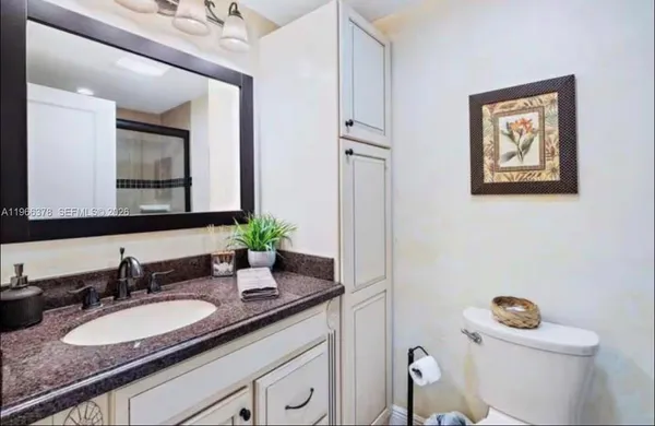 a bathroom with a granite countertop sink and a mirror with toilet