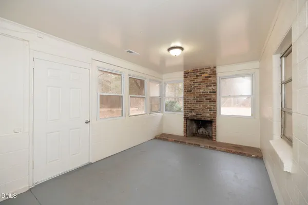 an empty room with windows and fireplace