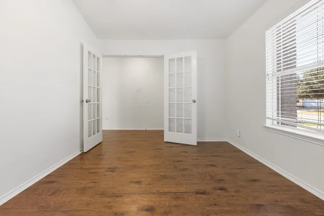 a view of an empty room with wooden floor and a window