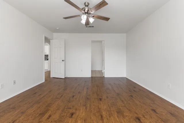 a view of an empty room with window and a ceiling fan