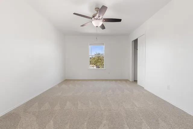 an empty room with windows and a ceiling fan
