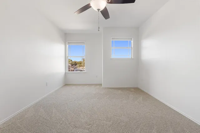 an empty room with a ceiling fan and a window