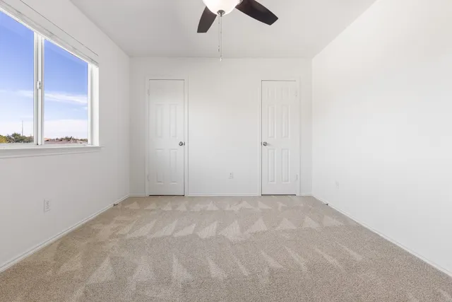 an empty room with windows and fan