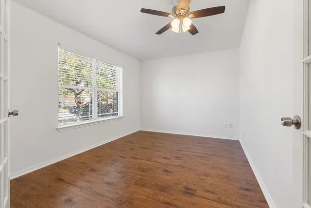 a view of an empty room with wooden floor and a window