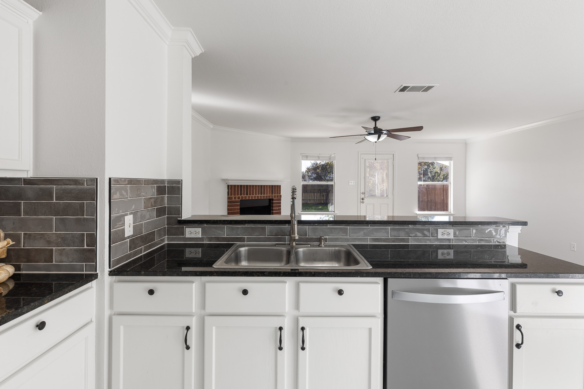 406 Golden Gate Drive Leander, TX 78641 - Photo 40 of 40 Kitchen with white cabinetry, stainless steel dishwasher, open floor plan, a peninsula, and crown molding