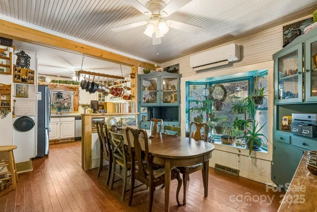 a dining room with stainless steel appliances kitchen island granite countertop a table chairs and a chandelier