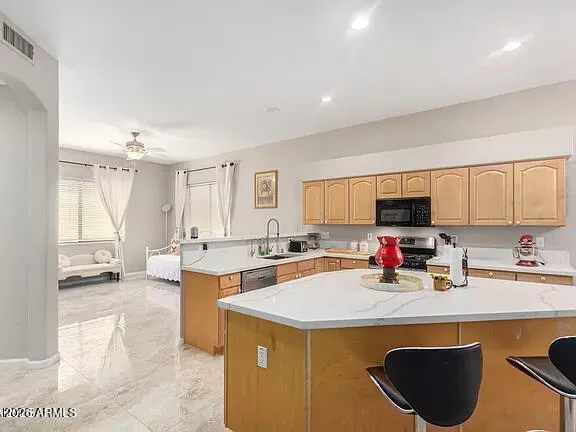 a view of a kitchen with kitchen island a sink a stove and a refrigerator