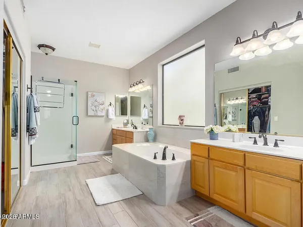 a large white bathroom with a double vanity sink a mirror and a bathtub