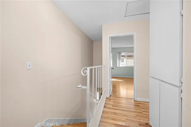 a view of a hallway with wooden floor and a bathroom