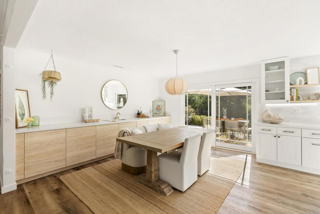 1427 Avocado Road Oceanside, CA 92054 - Photo 18 of 57 a kitchen with a stove a sink dishwasher and a dining table with wooden floor