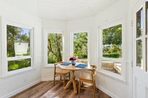 a dining room with wooden floor a chandelier a glass table and chairs