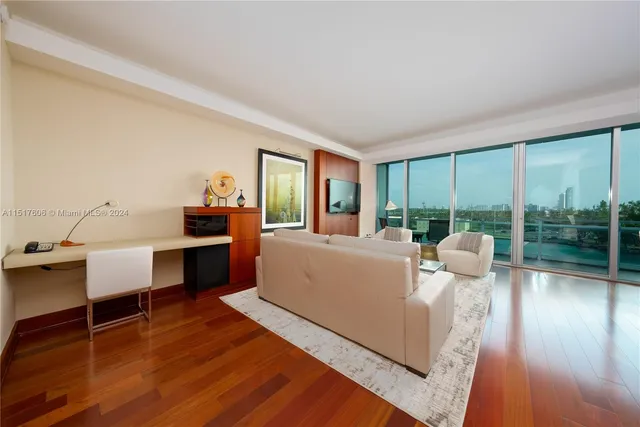 a living room with furniture large windows and wooden floor