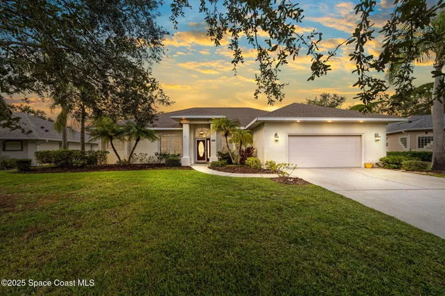 a front view of a house with a garden and trees