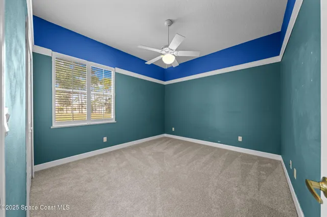a view of an empty room with window and chandelier fan