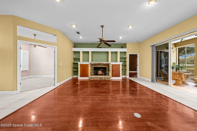 a view of an empty room with wooden floor fireplace and a window