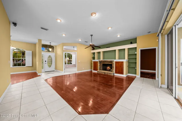 a view of an empty room with kitchen and a window