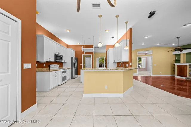 a large kitchen with stainless steel appliances kitchen island granite countertop a sink and cabinets