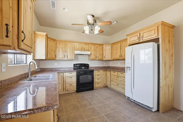 a kitchen with stainless steel appliances granite countertop a sink a stove a refrigerator cabinets and a dining table