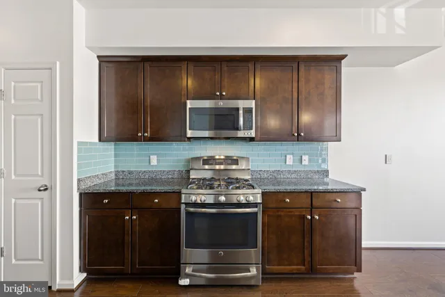 a kitchen with granite countertop wood cabinets and stainless steel appliances