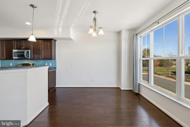 a view of kitchen with granite countertop stainless steel appliances and wooden floor