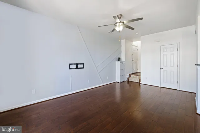 an empty room with wooden floor fan and windows