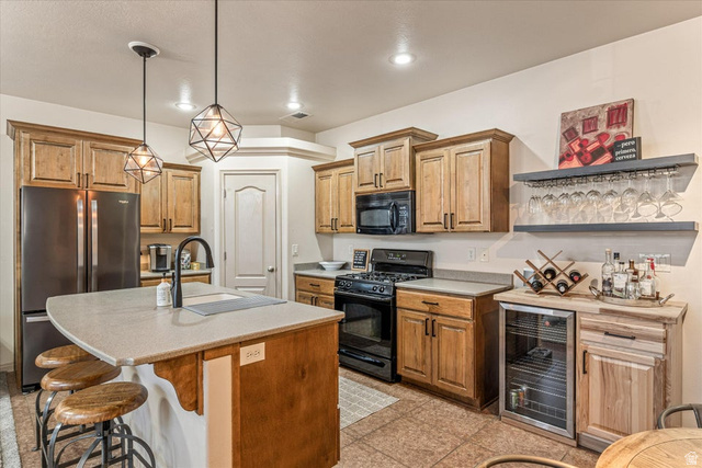 345 North 2450th Street East, Unit 152 St. George, UT 84790 - Photo 11 of 40 Kitchen with black appliances, wine cooler, a kitchen island with sink, pendant lighting, and a kitchen breakfast bar