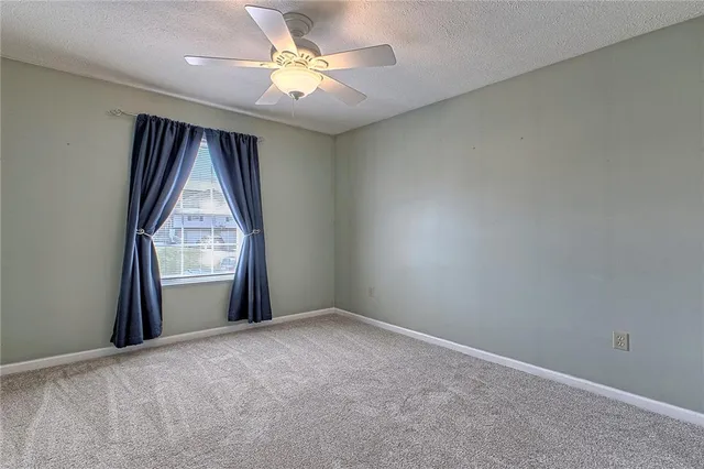 an empty room with windows and fan