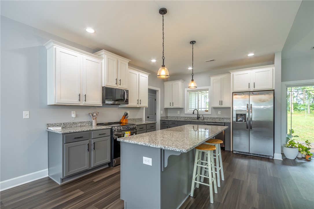 3080 McGee Road Iva, SC 29655 - Photo 8 of 49 A contemporary kitchen features a spacious island with bar seating, ample cabinetry, and stainless steel appliances.