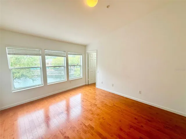 an empty room with wooden floor and windows