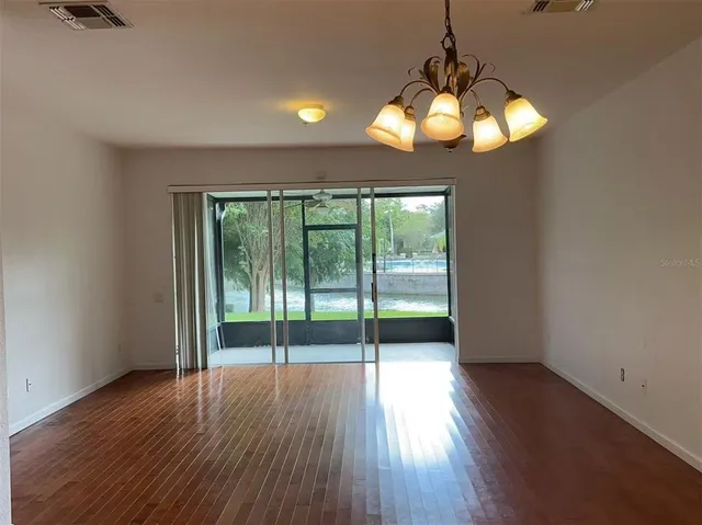 a view of an empty room with wooden floor and a large window