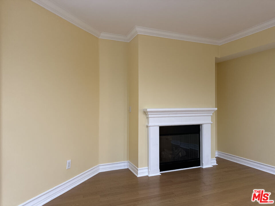 122 North Clark Drive, Unit 105 West Hollywood, CA 90048 - Photo 13 of 28 a view of an empty room with wooden floor and a fireplace