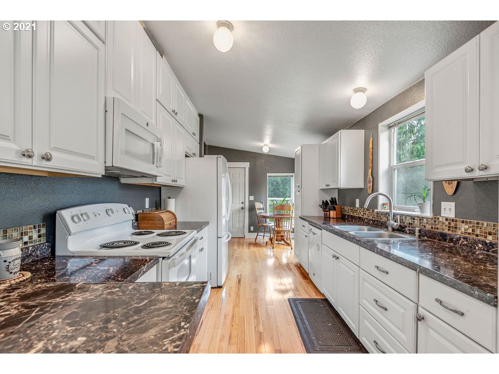 109 Highland Road Winlock, WA 98596 - Photo 17 of 28 a open kitchen with granite countertop a sink dishwasher stove and white cabinets with wooden floor