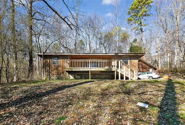 a view of a house with large trees and a wooden fence