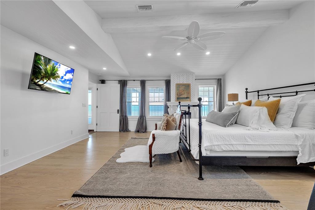 8241 Main Street Bokeelia, FL 33922 - Photo 62 of 100 a spacious bedroom with a bed a couch and a flat screen tv