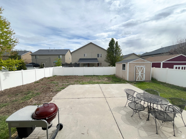 297 West Bricker Road Draper, UT 84020 - Photo 22 of 25 Fenced backyard with a storage shed, outdoor dining area, a patio, and a residential view