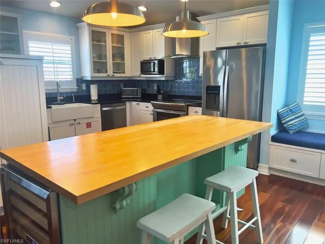 a kitchen with stainless steel appliances kitchen island granite countertop a table chairs and a refrigerator