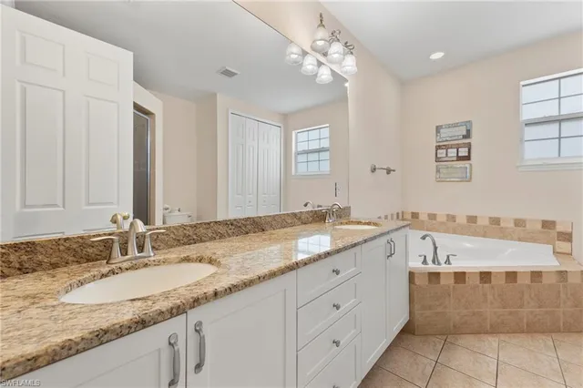 a bathroom with a granite countertop double vanity sink and mirror