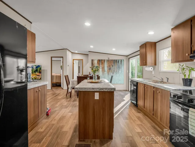 a kitchen with stainless steel appliances granite countertop wooden cabinets a sink dishwasher a stove and a refrigerator
